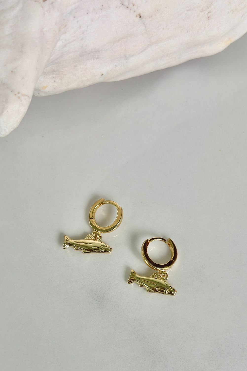 Gold sport fish charm hoop earrings by Maritt Row, flat lay product photo