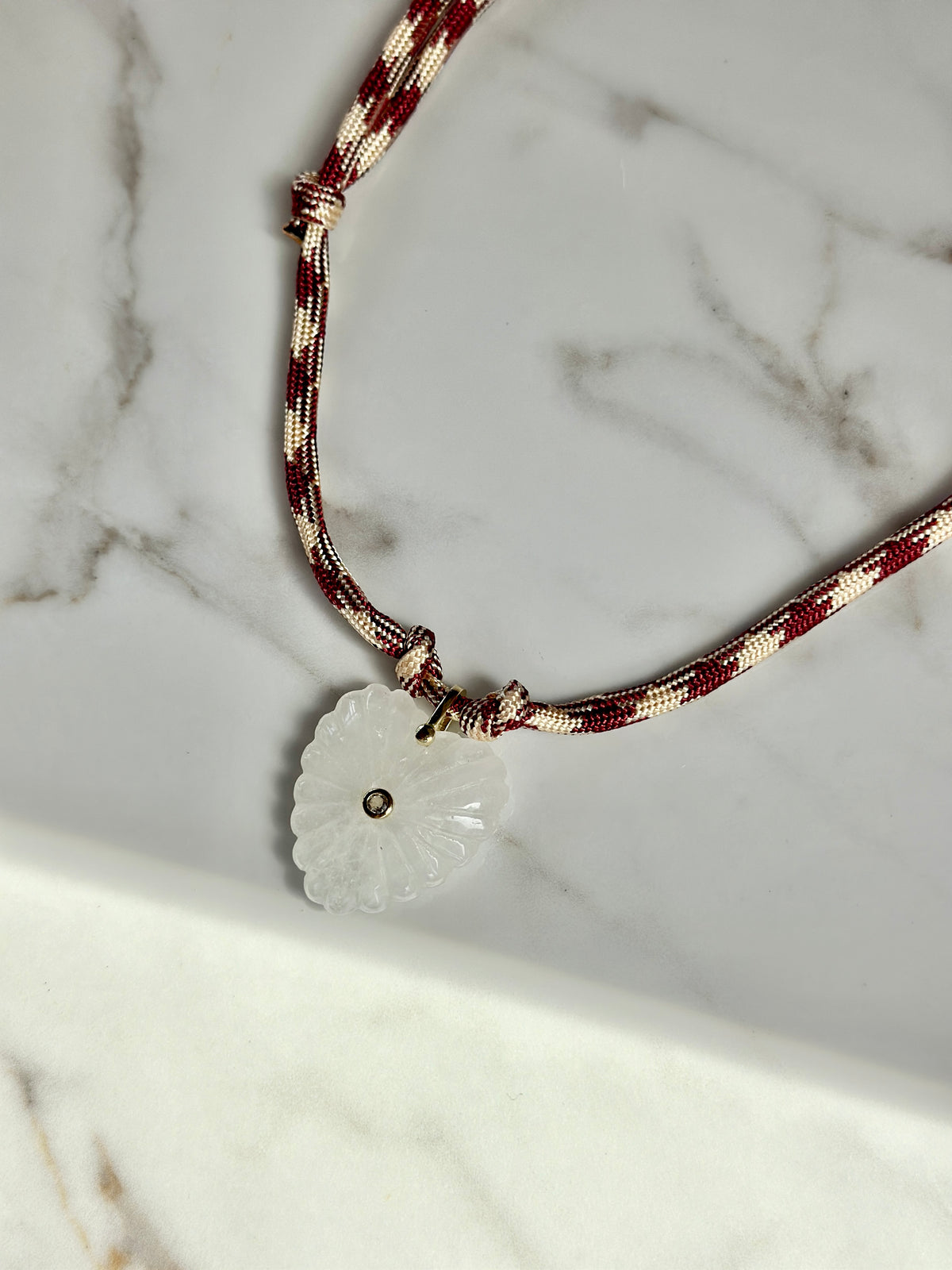 “Handmade adjustable burgundy and cream paracord necklace with natural quartz heart pendant.”
