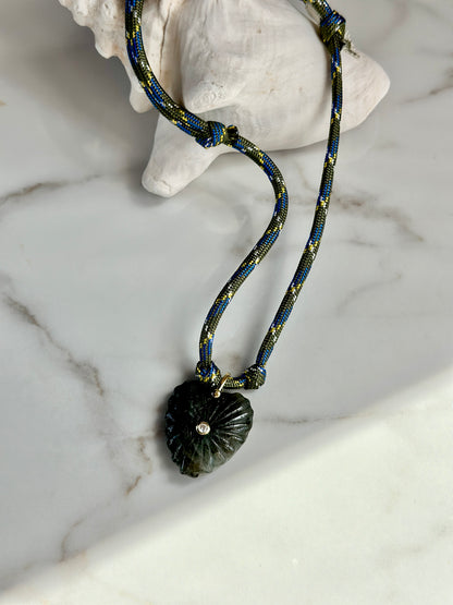 Close-up of dark green carved stone pendant with sparkling CZ accent on an olive and blue paracord necklace.