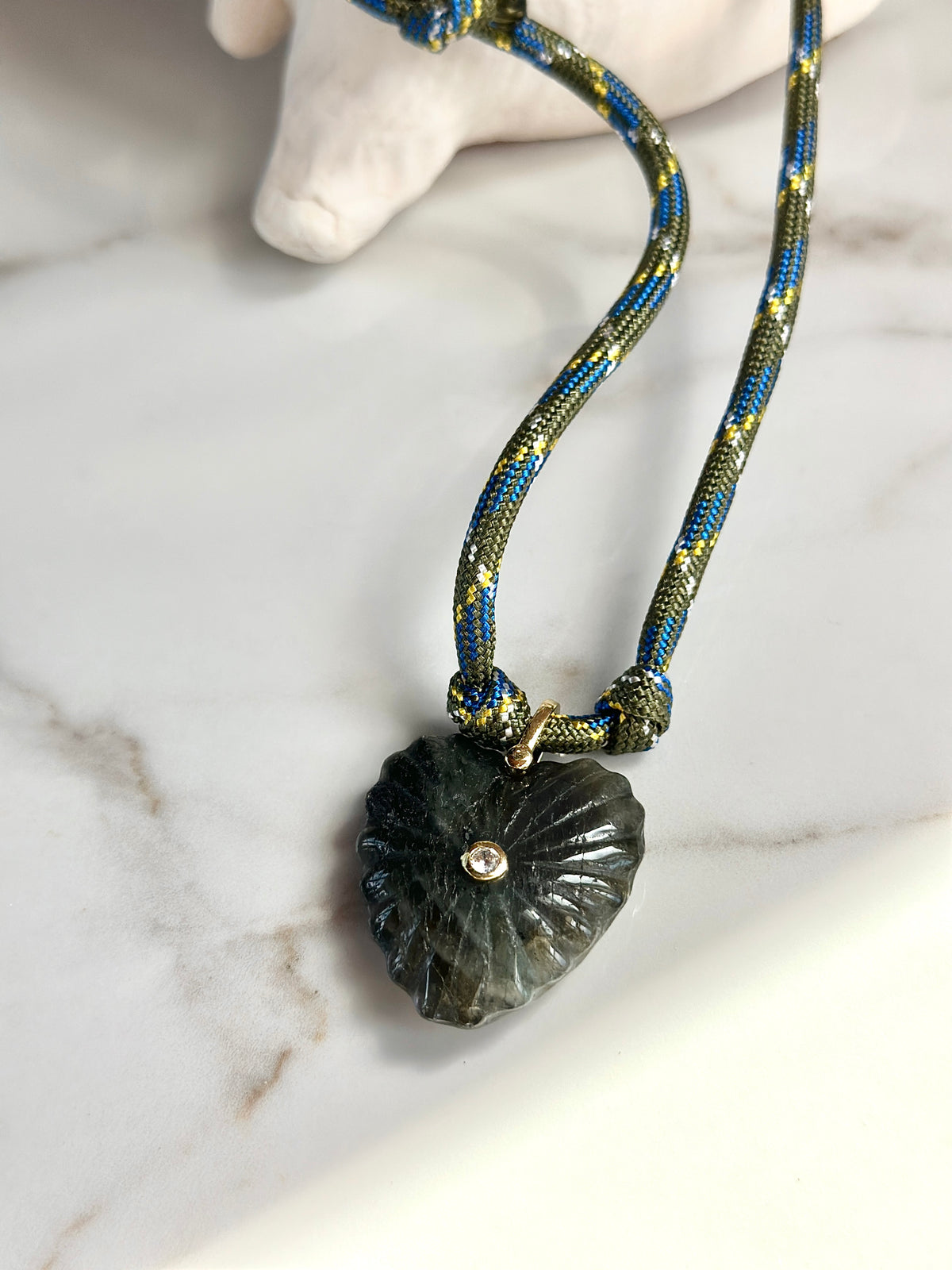 Dark green carved stone pendant necklace with olive and blue woven paracord cord and gold-tone details.