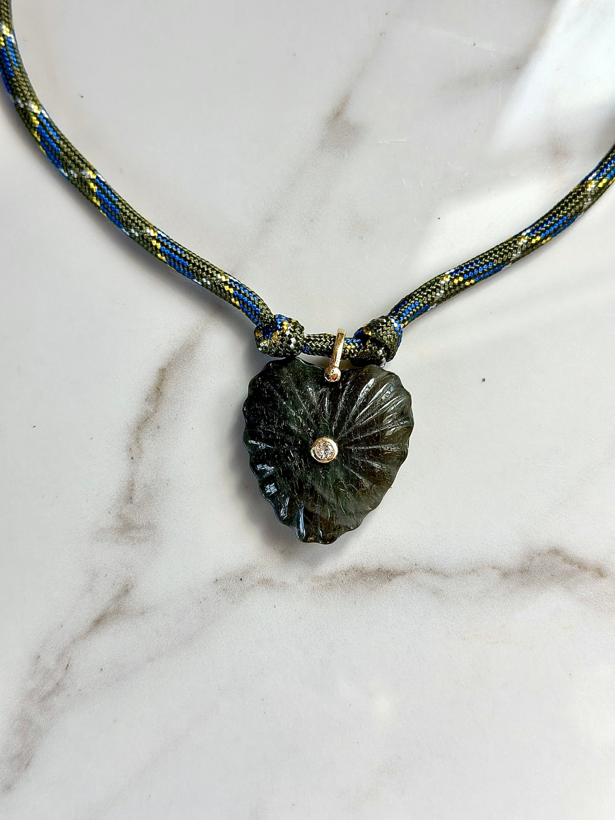 Olive and blue patterned paracord necklace with dark green carved stone pendant and CZ center accent.
