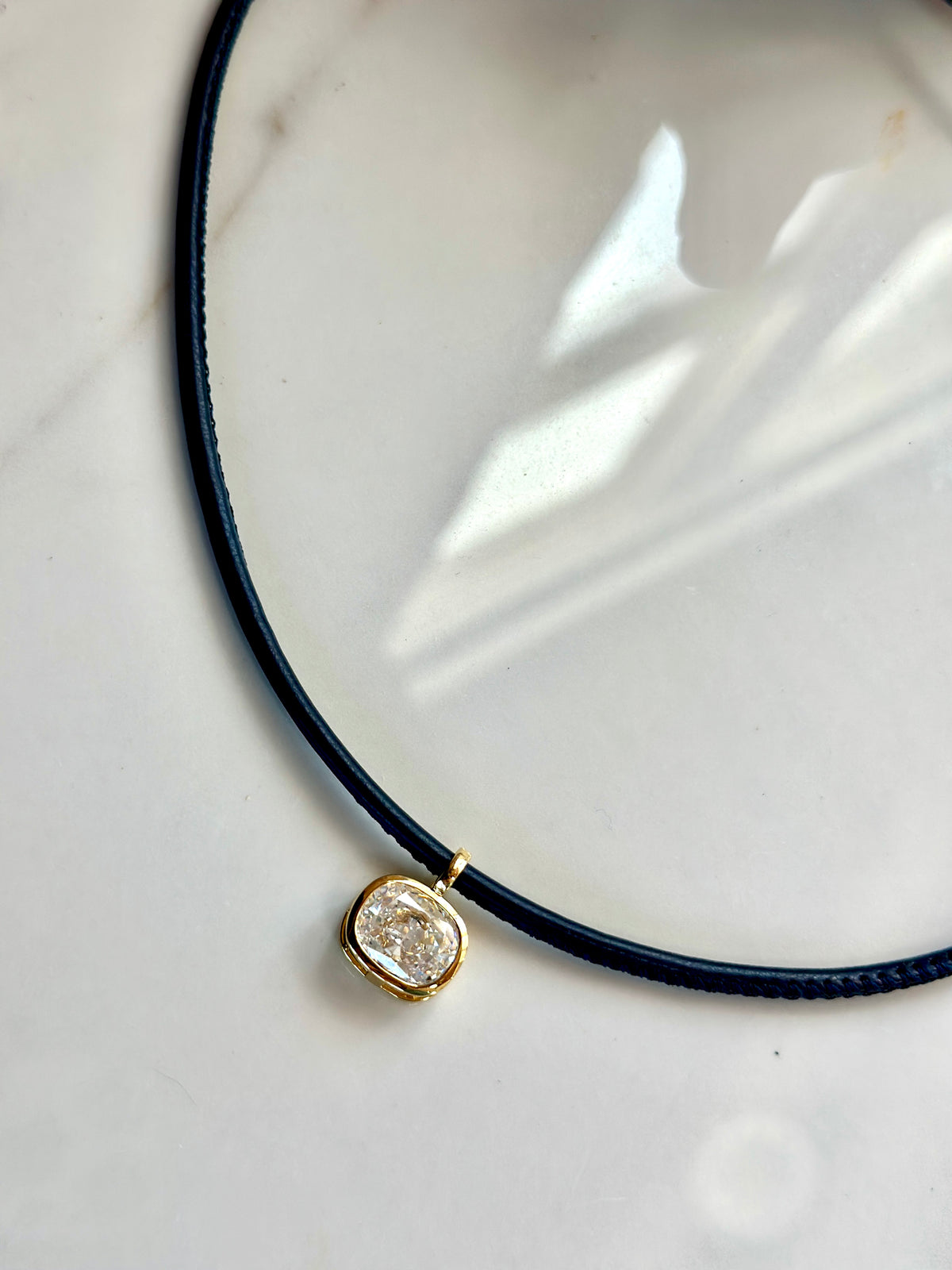 Navy cord necklace with sparkling CZ pendant and gold clasp closure.
