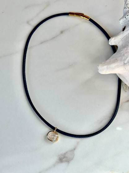 Navy cord necklace with gold-set cushion cubic zirconia pendant.
