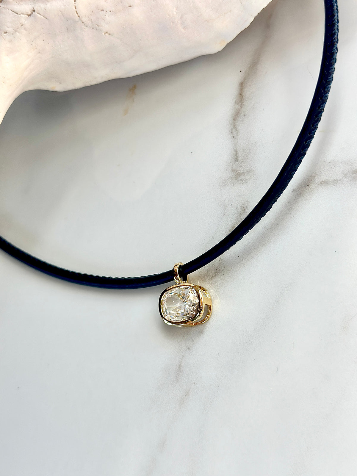 Navy cord pendant necklace with sparkling cushion CZ in a polished gold setting.
