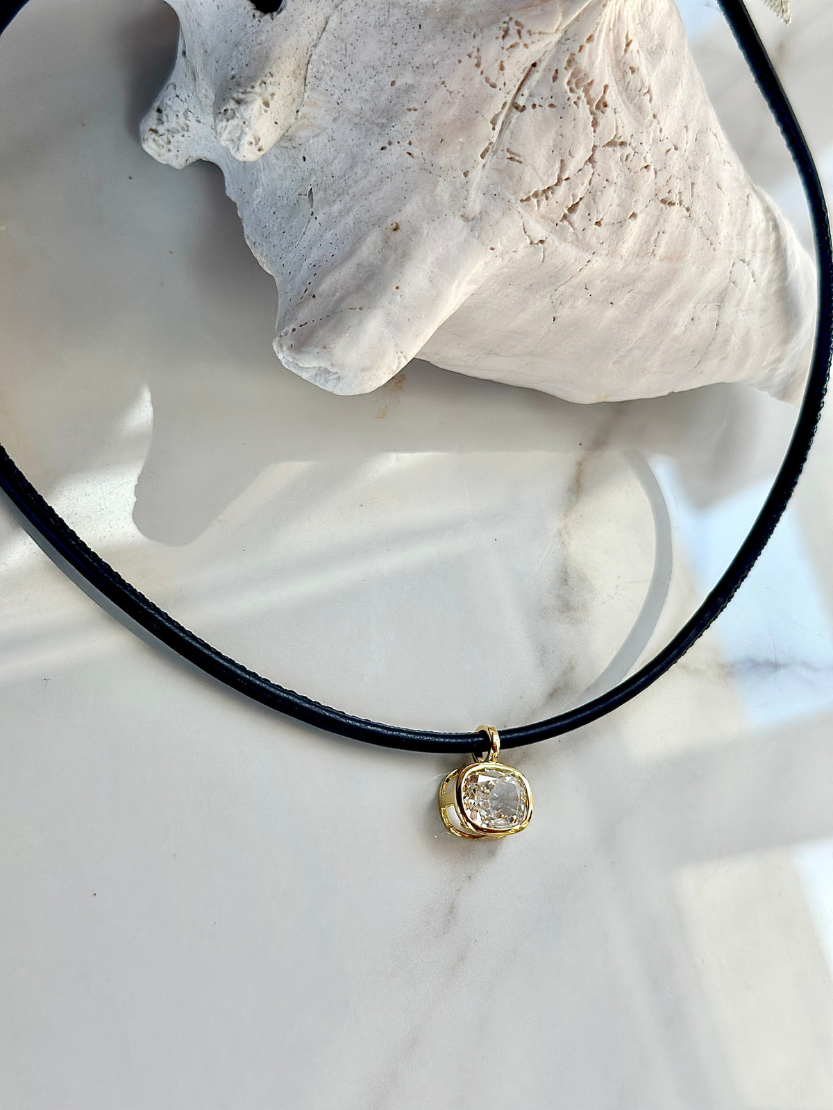 Navy necklace with gold-set cubic zirconia pendant styled with coastal decor.
