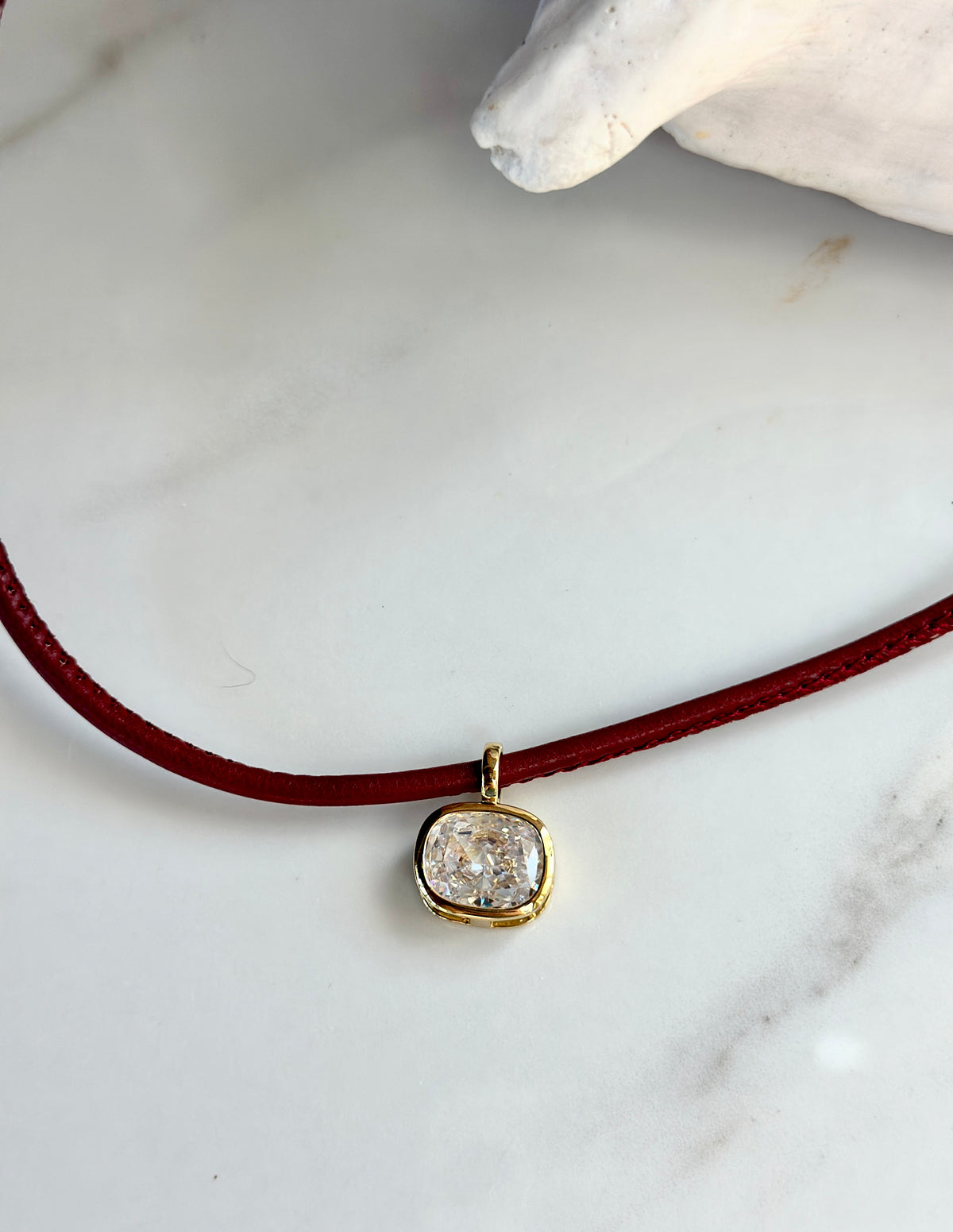Red necklace with cushion-cut CZ pendant and polished gold setting.
