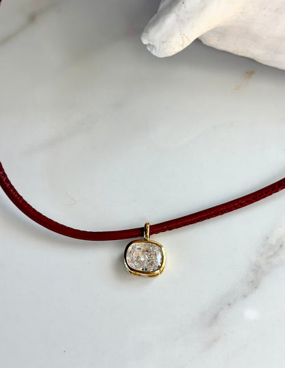 Red necklace with cushion-cut CZ pendant and polished gold setting.
