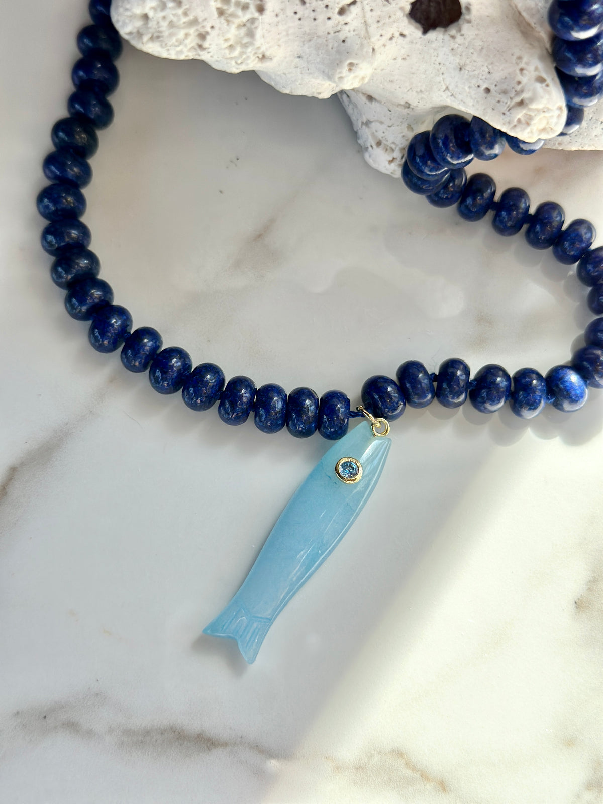 Blue gemstone fish necklace with carved aqua fish pendant and gold accent

