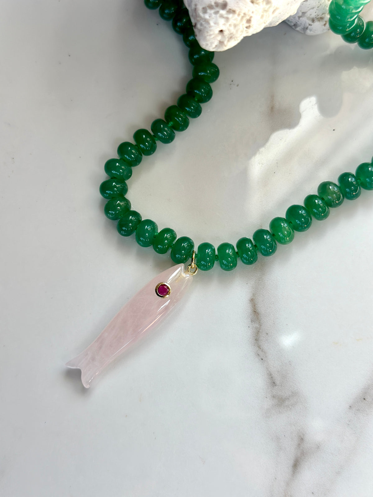 Green gemstone necklace with pale pink carved fish pendant and gold detailing
