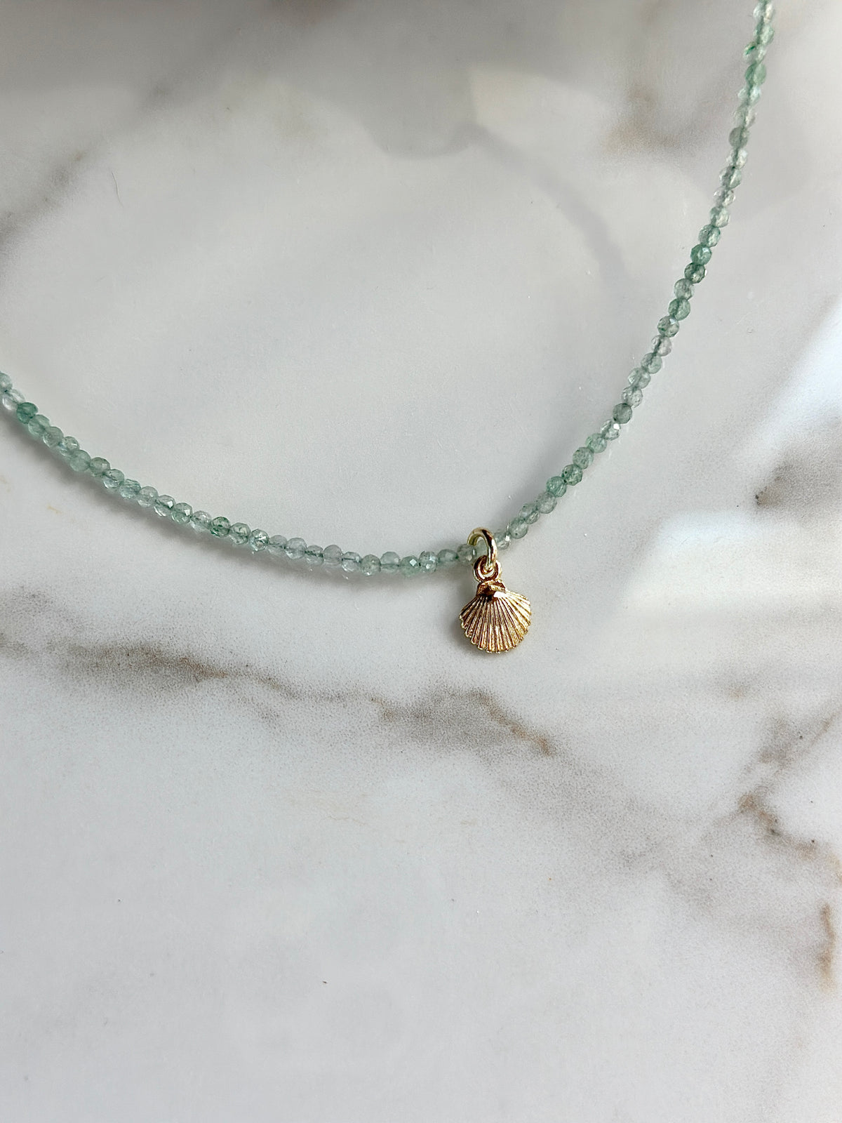Pale green Green Strawberry gemstone bead necklace with a petite gold shell charm.
