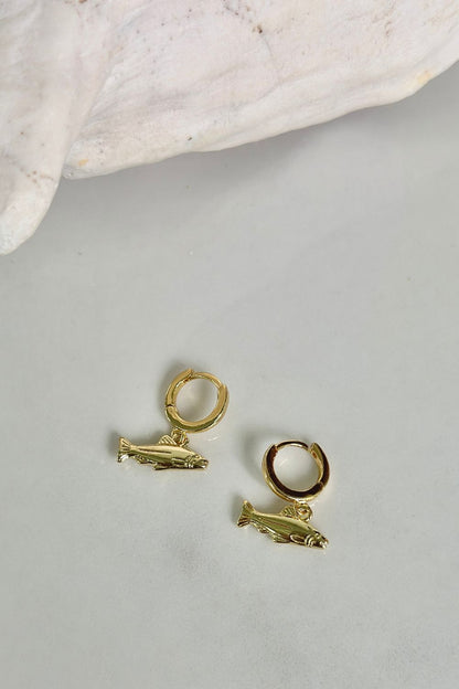 Gold sport fish charm hoop earrings by Maritt Row, flat lay product photo